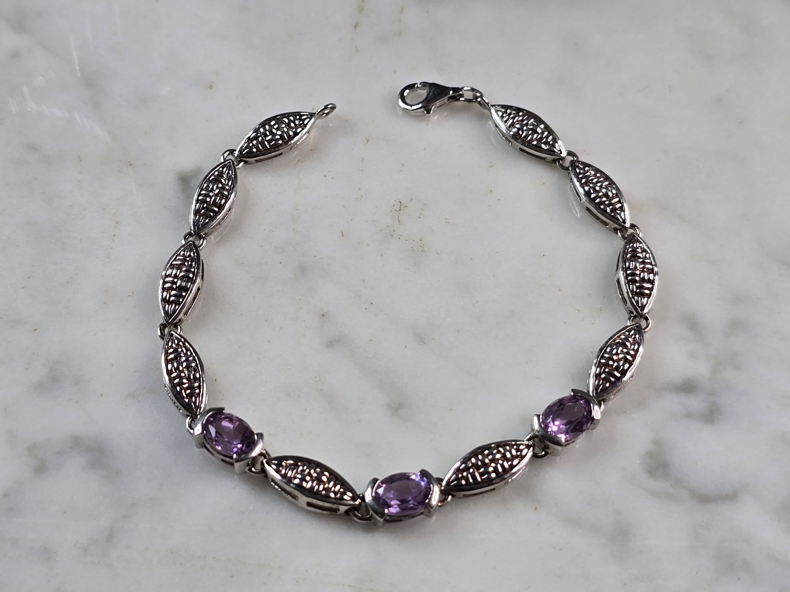 Womens Vintage Estate Sterling Silver Amethyst Bracelet: A WOMENS VINTAGE ESTATE STERLING SILVER AMETHYST COLORED BRACELET. BRACELET MEASURES 7" LONG BY 3/16" WIDE, AND WEIGHS 8.2g. NOT SURE IF STONES ARE NATURAL OR MAN MADE. THIS WOULD MAKE A LOVELY GIFT F