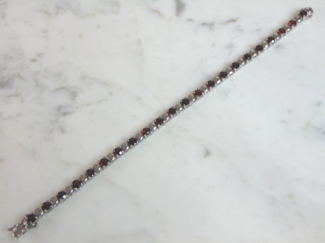Womens Vintage Estate Sterling Silver Garnet Bracelet: A WOMENS VINTAGE STERLING SILVER GARNET BRACELET. NOT SURE IF STONES ARE REAL OR MAN MADE. BRACELET MEASURES 7 3/8" LONG AND 1/8" WIDE AND WEIGHS 13.1g. WOULD MAKE A LOVELY GIFT FOR THAT SOMEONE SPECI