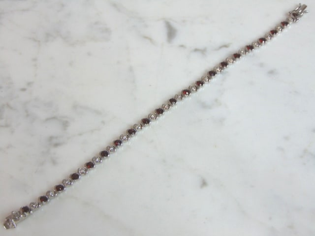 Womens Vintage Estate Sterling Silver Garnet Bracelet: A WOMENS VINTAGE STERLING SILVER GARNET BRACELET. NOT SURE IF STONES ARE REAL OR MAN MADE. BRACELET MEASURES 7 5/8" LONG AND 1/4" WIDE AND WEIGHS 12.2g. WOULD MAKE A LOVELY GIFT FOR THAT SOMEONE SPECI