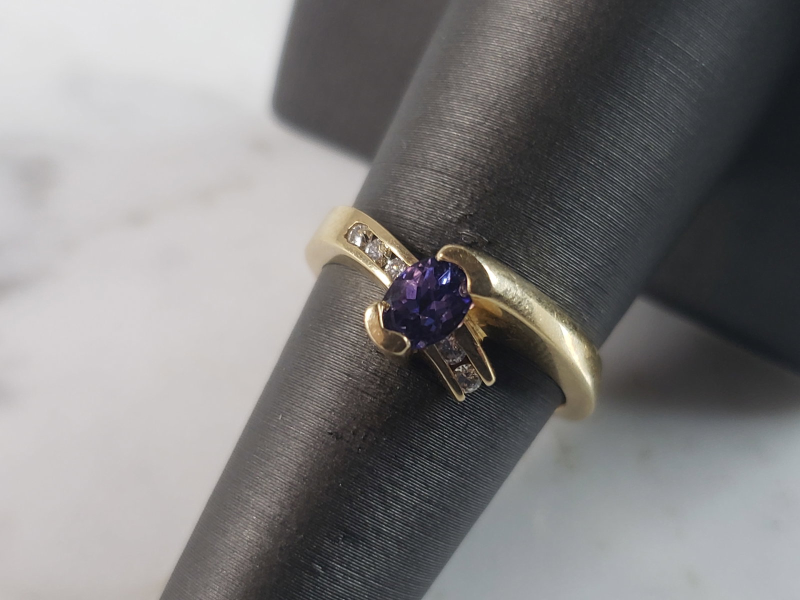 Womens Vintage Estate 14K Yellow Gold Tanzanite Diamond Ring: A WOMENS VINTAGE ESTATE 14K GOLD RING WITH A TANZANITE COLORED STONE AND DIAMONDS. RING IS A SIZE 7.0 AND WEIGHS 4.4g. THERE ARE ABOUT .10cts OF DIAMONDS. THE CENTER STONE IS ABOUT .20cts. THE RING MA