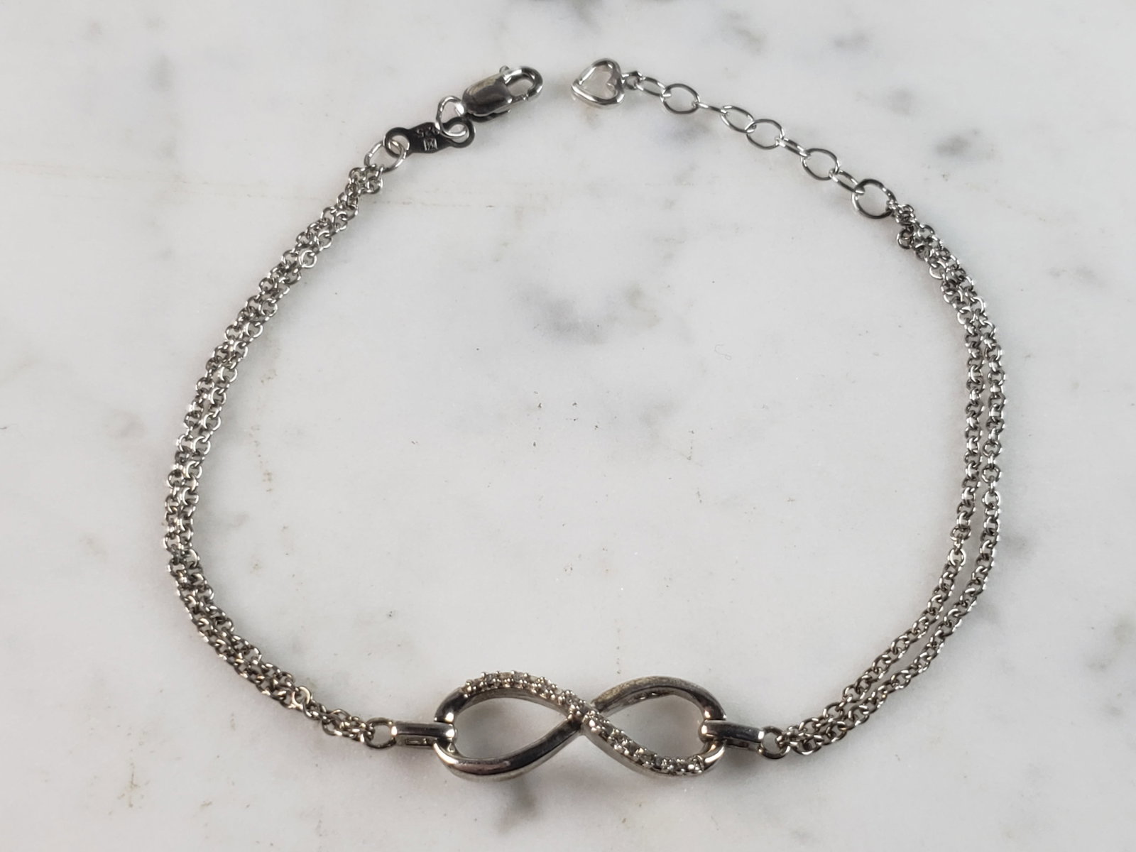 Womens Vintage Estate Sterling Silver Diamond Infinity Bracelet: A WOMENS VINTAGE ESTATE STERLING SILVER DIAMOND INFINITY BRACELET. BRACELET MEASURES 7 1/2" LONG AND 3/8" WIDE AND WEIGHS 3.1g. THERE ARE ABOUT .08cts OF DIAMONDS. WOULD MAKE A LOVELY GIFT FOR THAT SO