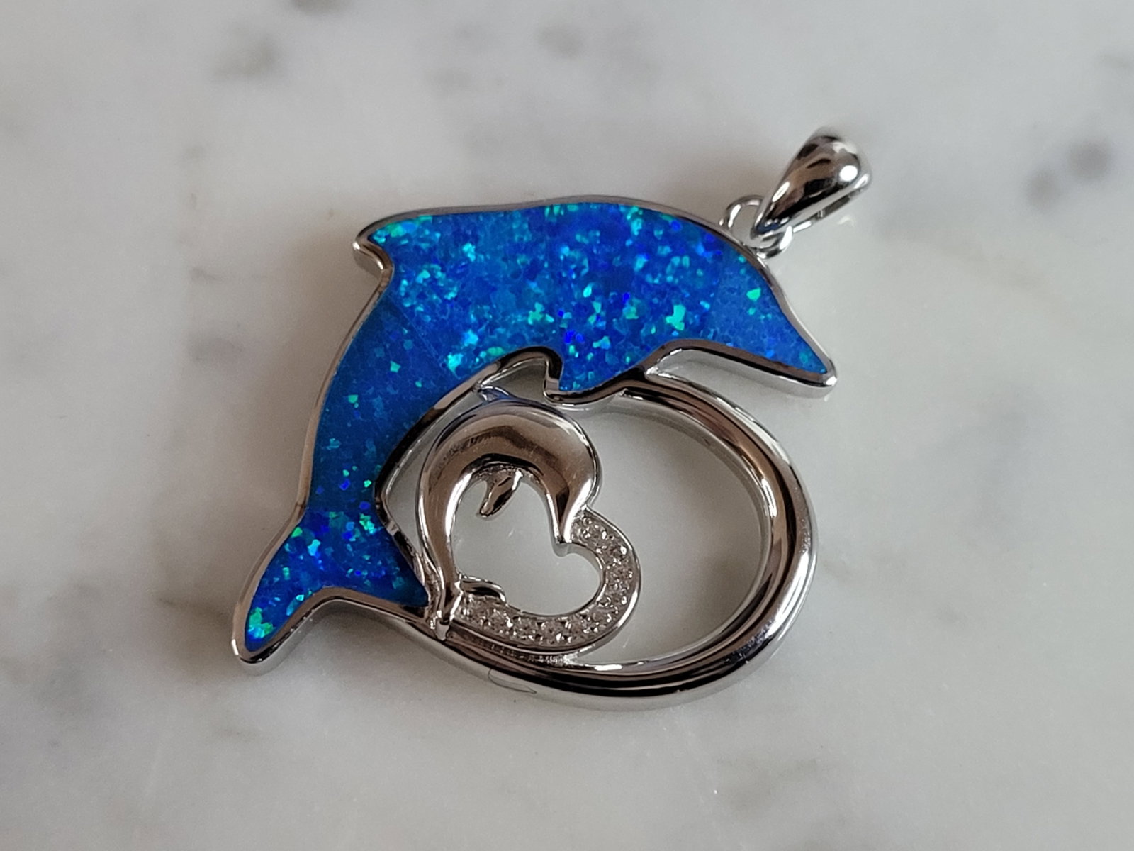 Womens Sterling Silver Blue Opal Dolphin Pendant: A WOMENS STERLING SILVER BLUE OPAL DOLPHIN HEART PENDANT. NOT SURE IF STONES ARE REAL OR MAN MADE. THE PENDANT WEIGHS 7.1g AND MEASURES 1 3/8" LONG BY 1" WIDE. MAKES A GREAT GIFT FOR THAT SOMEONE SPEC