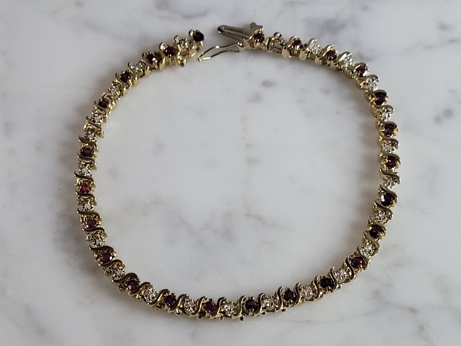 Womens Vintage Estate 12k Yellow Gold Diamond Ruby Tennis Bracelet: A WOMENS VINTAGE ESTATE 12K YELLOW GOLD DIAMOND & RUBY TENNIS BRACELET. BRACELET IS 7 1/2" LONG BY 3/16" WIDE, AND WEIGHS 10.8g. THERE ARE 24 TINY DIAMONDS IN THIS BRACELET. BRACELET IS MARKED 14K BUT