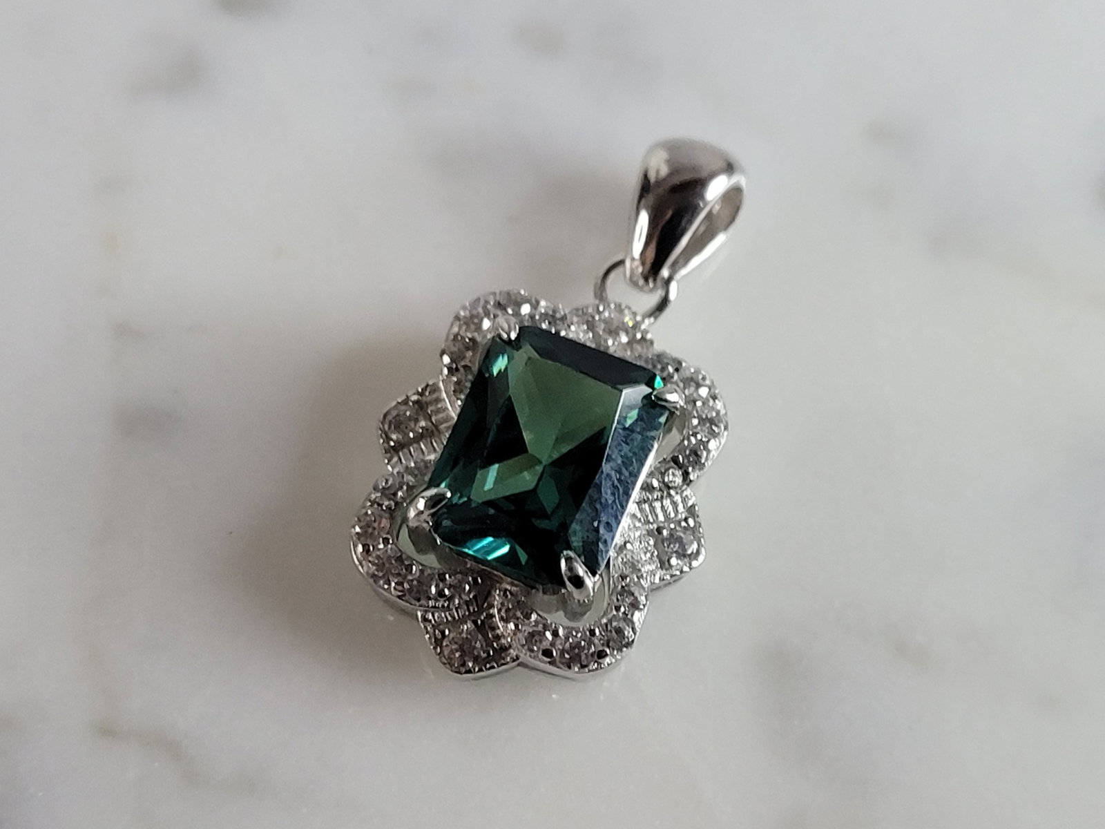 Womens Estate Sterling Silver Modernist CZ Pendant: A WOMENS ESTATE STERLING SILVER MODERNIST CZ PENDANT WITH AN EMERALD COLORED STONE. PENDANT WEIGHS 2.7g AND MEASURES 5/8" LONG BY 1/2" WIDE. MAKES A GREAT GIFT FOR THAT SOMEONE SPECIAL. ANY QUESTIONS,