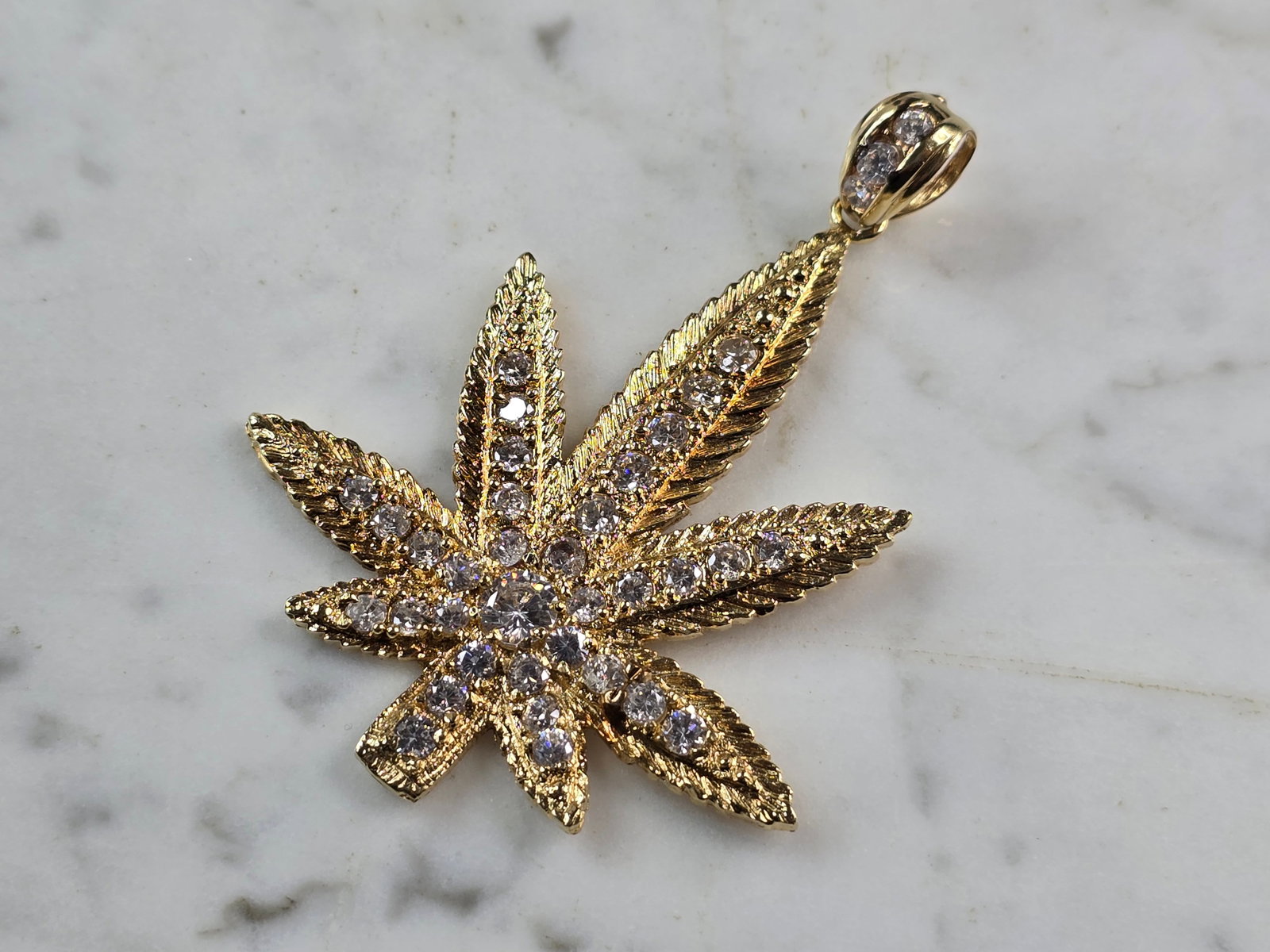 Vintage Estate 14K Yellow Gold CZ Marijuana Pot Leaf Pendant: A VINTAGE ESTATE 14K YELLOW GOLD MARIJUANA LEAF PENDANT ACCENTED WITH CZ STONES. THE PENDANT WEIGHS 15.5g, AND MEASURES 2 7/8" BY 2 1/16". PENDANT IS STAMPED "14K". MAKES A GREAT GIFT FOR THAT SOMEONE