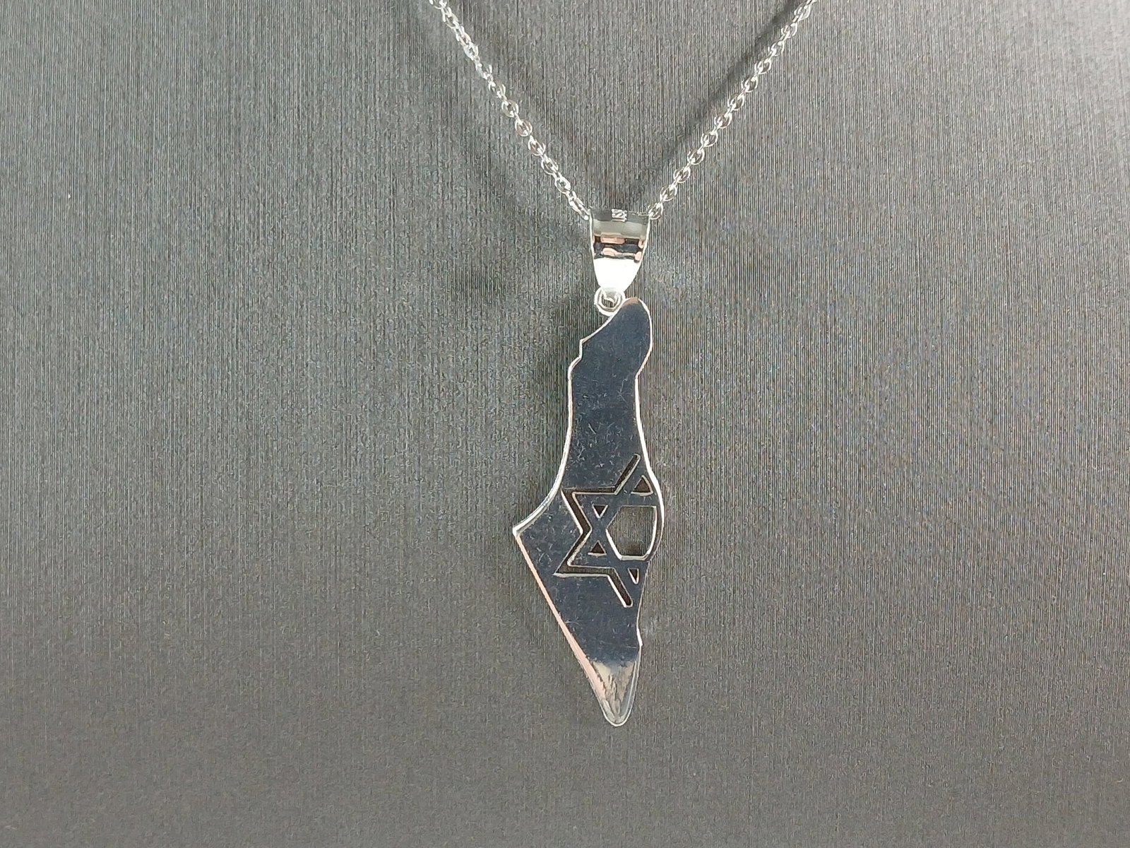Sterling Silver Jewish Judaica Star of David Israel Pendant Necklace: A STERLING SILVER JUDAICA STAR OF DAVID PENDANT IN THE SHAPE OF ISRAEL. THE PENDANT WITH NECKLACE WEIGHS 4.1g. THE NECKLACE MEASURES 18" LONG AND IS ADJUSTABLE TO 16" LONG. THE PENDANT MEASURES 1 3/4"