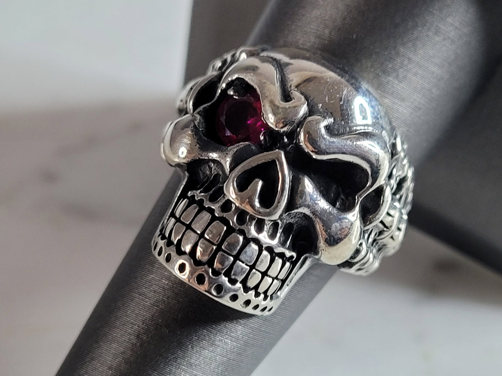 Mens Sterling Silver Ruby Eyed Skull Ring: A MENS STERLING SILVER RUBY EYED SKULL RING. THE TOTAL WEIGHT IS 12.9g, AND IS A SIZE 8.75. THE WIDTH OF THE RING FACE IS 7/8". SKULL IS INTENDED TO HAVE ONE EYE. STONE TESTED RUBY ON OUR PRESIDIUM GE