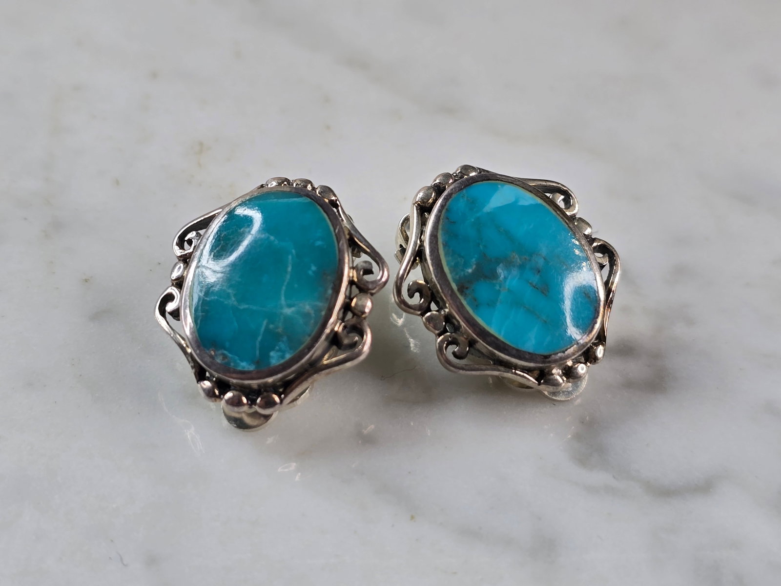 Womens Vintage Estate Sterling Silver Turquoise Clip On Earrings: A PAIR OF WOMENS VINTAGE ESTATE STERLING SILVER TURQUOISE CLIP ON EARRINGS. THE EARRINGS WEIGH 10.9g AND MEASURE 3/4" BY 5/8". NOT SURE IF STONES ARE NATURAL OR MAN MADE. AS YOU MAY BE ABLE TO SEE ONE