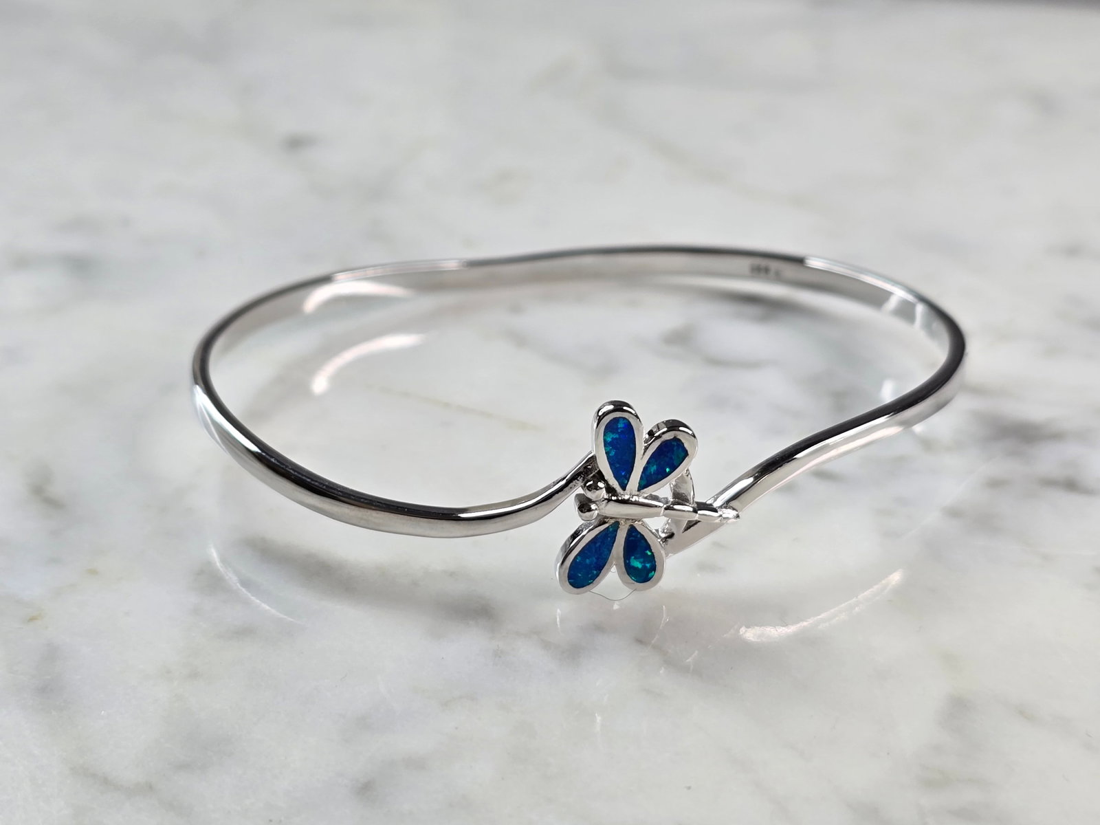 Womens Sterling Silver Blue Opal Dragonfly Bangle Bracelet: A WOMENS STERLING SILVER MODERNIST BLUE OPAL COLORED DRAGONFLY BANGLE BRACELET. THE BRACELET WEIGHS 12.0g AND MEASURES 8" IN CIRCUMFERENCE BY 5/8" WIDE. NOT SURE IF OPAL IS NATURAL OR MAN MADE. ANY QU