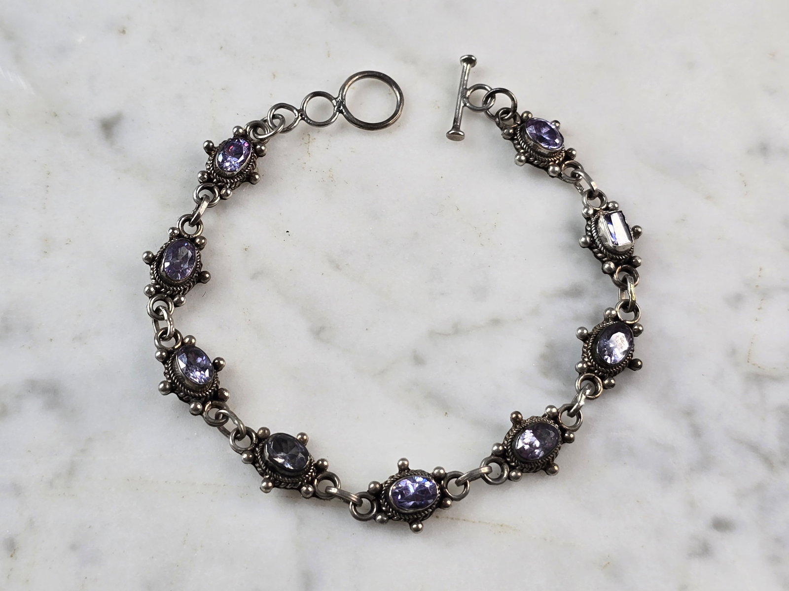 Womens Vintage Estate Sterling Silver Amethyst Bracelet: A WOMENS VINTAGE ESTATE STERLING SILVER AMETHYST BRACELET. BRACELET MEASURES 7 1/2" LONG BY 1/4" WIDE, AND WEIGHS 10.4g. NOT SURE IF STONES ARE REAL OR MAN MADE. THIS WOULD MAKE A LOVELY GIFT FOR THAT