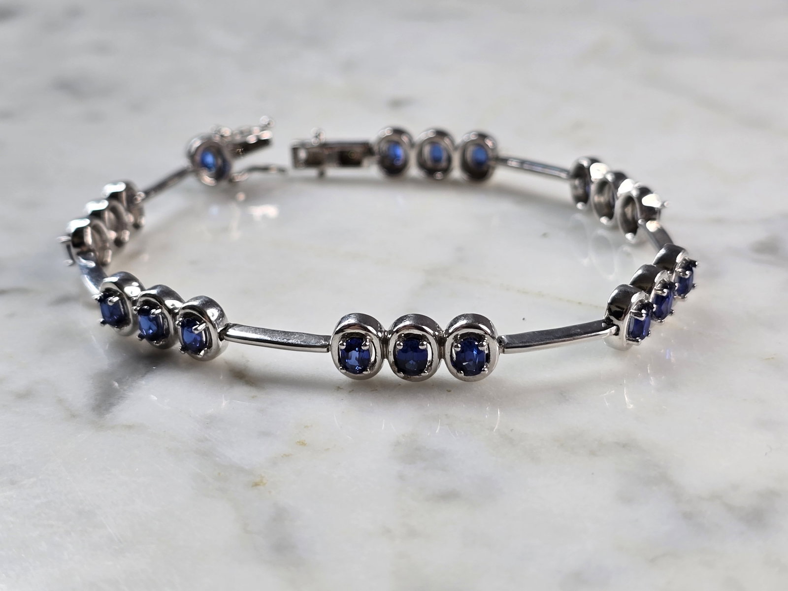 Womens Vintage Estate Sterling Silver Modernist Sapphire Bracelet: A WOMENS VINTAGE ESTATE STERLING SILVER MODERNIST TENNIS BRACELET WITH BLUE SAPPHIRE COLORED STONES. THE BRACELET MEASURES 7 1/2" LONG BY 1/4" WIDE, AND WEIGHS 13.1g. NOT SURE IF THE STONES ARE NATURA