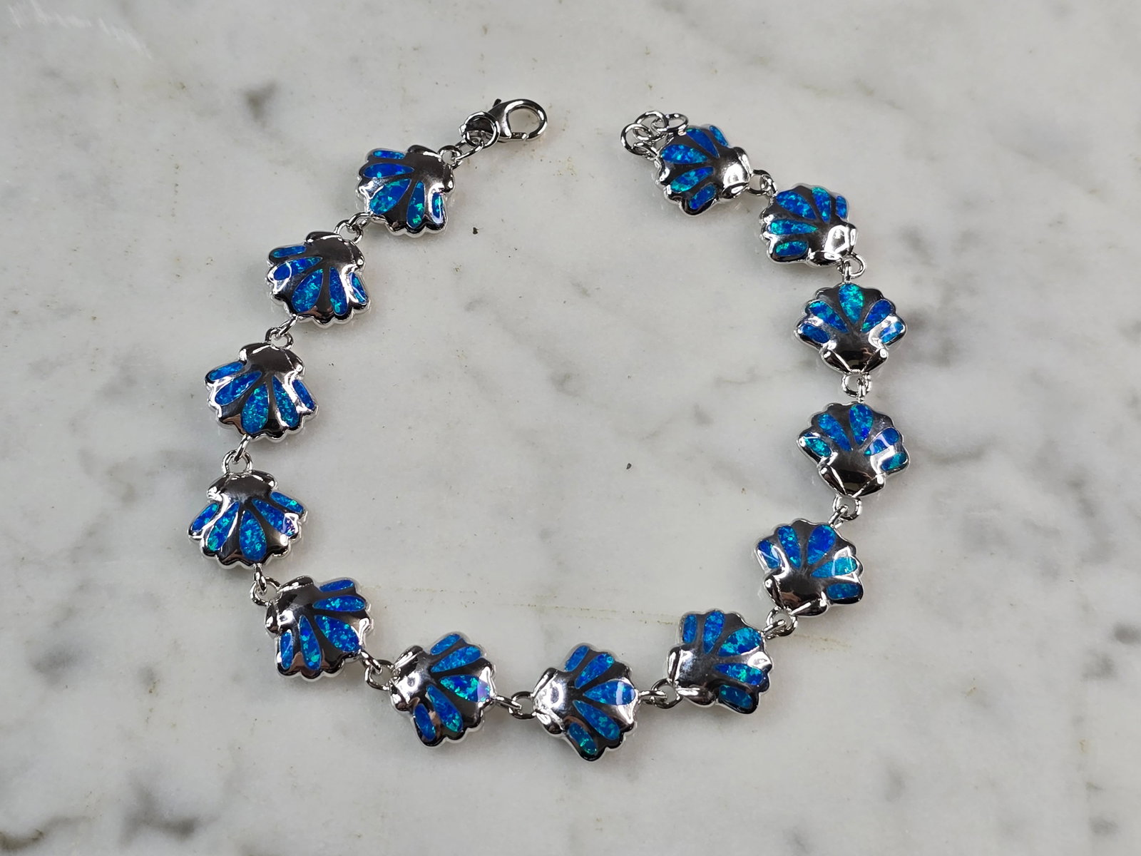 Womens Sterling Silver Blue Opal Sea Shell Bracelet: A WOMENS STERLING SILVER BLUE OPAL COLORED SEA SHELL BRACELET. THE BRACELET WEIGHS 14.2g AND MEASURES 7 3/4" LONG BY 3/8" WIDE. NOT SURE IF OPAL IS NATURAL OR MAN MADE. ANY QUESTIONS PLEASE DO NOT HES