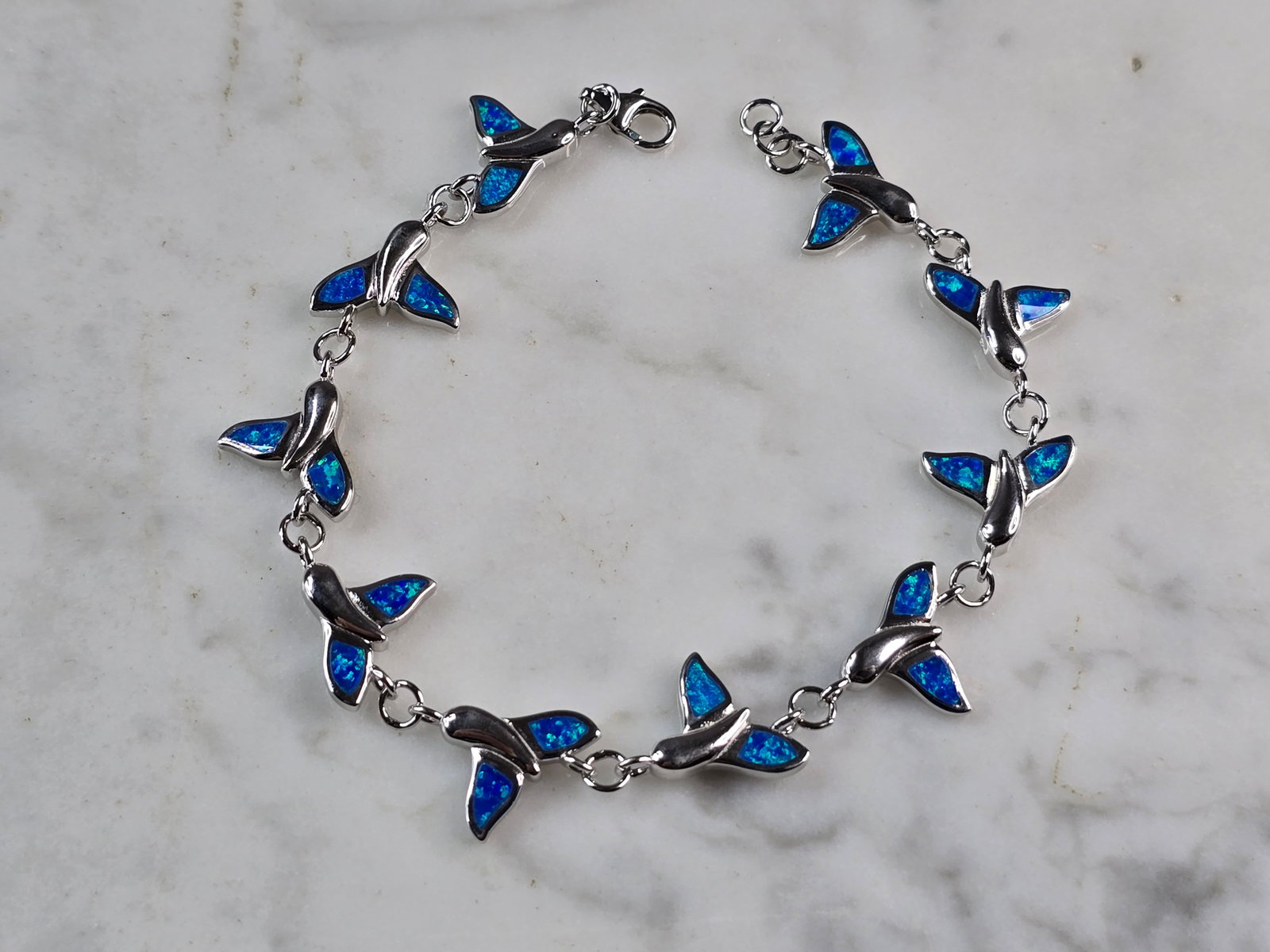 Womens Sterling Silver Blue Opal Whale Tail Ocean Bracelet: A WOMENS STERLING SILVER BLUE OPAL COLORED WHALE TAIL OCEAN BRACELET. THE BRACELET WEIGHS 11.9g AND MEASURES 7 1/2" LONG BY 1/2" WIDE. NOT SURE IF OPAL IS NATURAL OR MAN MADE. ANY QUESTIONS PLEASE DO 