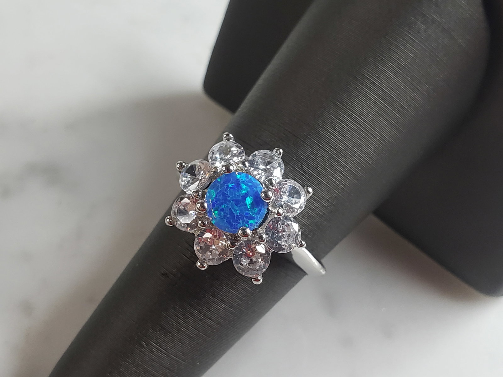 Womens Estate Sterling Silver Modernist Blue Opal Floral Ring: A WOMENS ESTATE STERLING SILVER MODERNIST OPAL COLORED FLORAL RING. THE RING IS A SIZE 7.75 AND WEIGHS 3.7g. WIDTH OF RING MEASURES 5/8". NOT SURE IF STONE IS NATURAL OR MAN MADE. THE RING MAKES A BEA