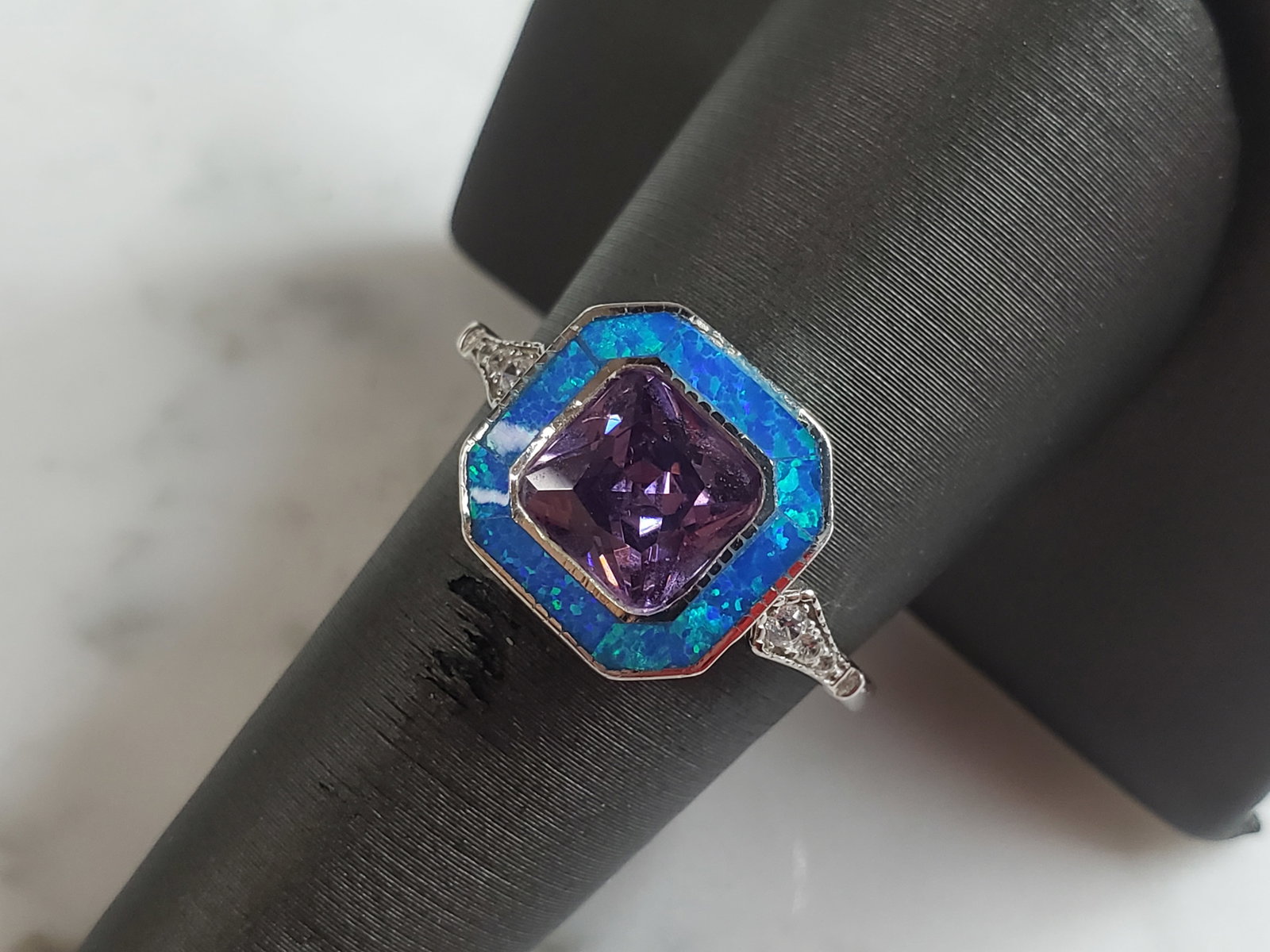 Womens Sterling Silver Modernist Blue Opal & Amethyst Ring: A WOMENS STERLING SILVER MODERNIST BLUE OPAL & AMETHYST COLORED RING. THE RING IS A SIZE 9.0, AND WEIGHS 3.8g. WIDTH OF RING MEASURES 1/2". NOT SURE IF STONE IS NATURAL OR MAN MADE. THE RING MAKES A B