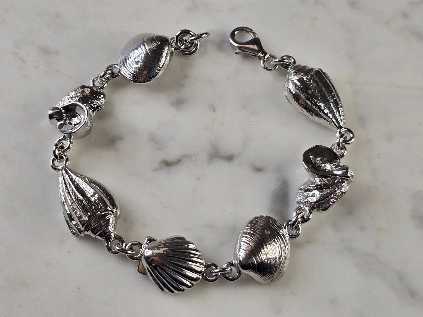 Womens Vintage Estate Sterling Silver Seashell Link Bracelet: A WOMENS VINTAGE ESTATE STERLING SILVER SEASHELL LINK BRACELET. THE BRACELET WEIGHS 25.9g, AND MEASURES 7 3/4" LONG BY 5/8" WIDE. THIS MAKES A WONDERFUL GIFT FOR THAT SOMEONE SPECIAL. BE SURE TO CHECK