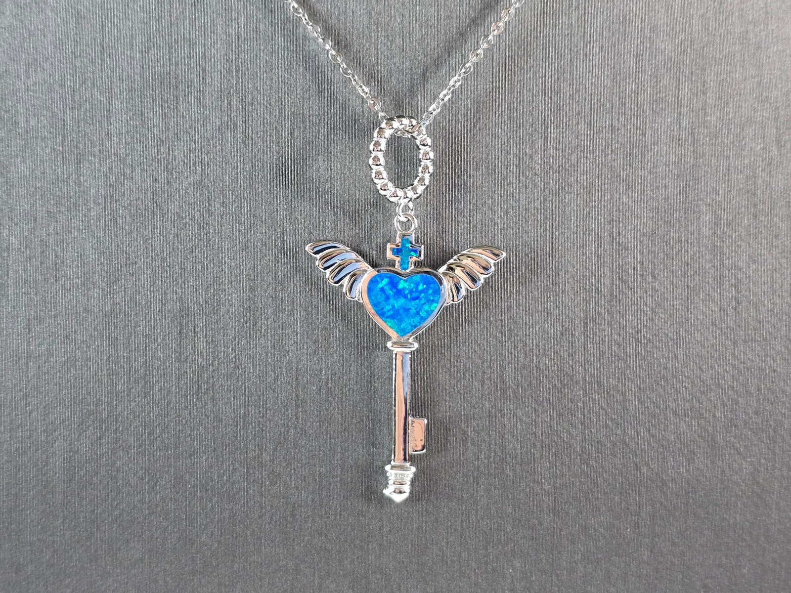 Womens Sterling Silver Blue Opal Winged Cross Heart Pendant Necklace: A WOMENS STERLING SILVER BLUE OPAL WINGED CROSS HEART PENDANT. THE PENDANT WITH NECKLACE WEIGHS 5.0g. THE PENDANT MEASURES 1 3/4" LONG BY 1" WIDE, AND THE NECKLACE MEASURES 18" LONG, ADJUSTABLE TO 16"