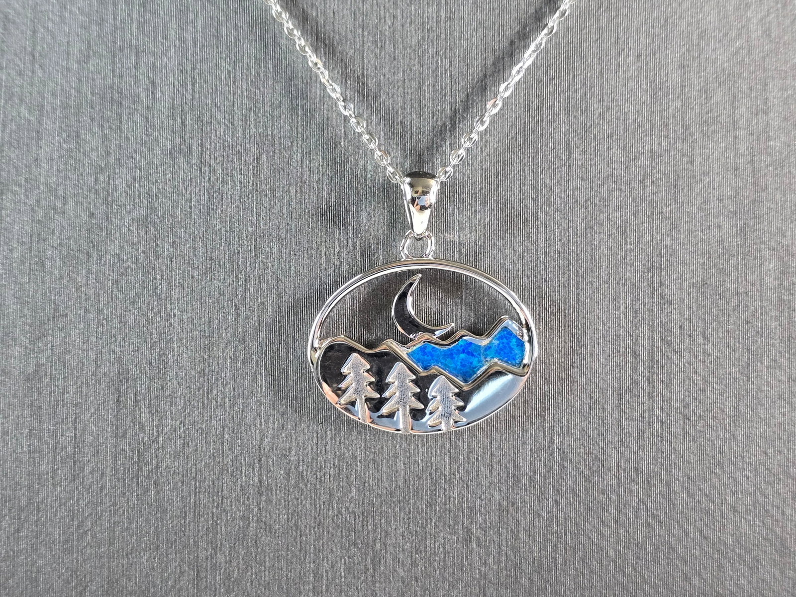 Womens Sterling Silver Blue Opal Mountain Moon Tree Pendant Necklace: A WOMENS STERLING SILVER BLUE OPAL MOUNTAIN MOON PENDANT. THE PENDANT WITH NECKLACE WEIGHS 5.4g. THE PENDANT MEASURES 7/8" LONG BY 7/8" WIDE. THE NECKLACE MEASURES 18" LONG AND IS ADJUSTABLE TO 16" LO