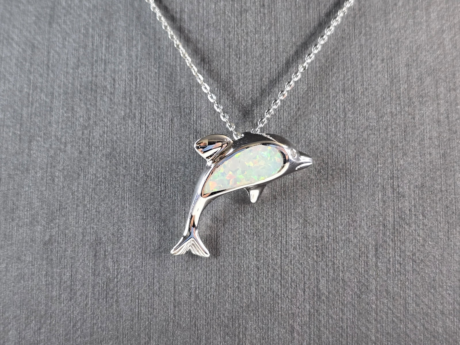 Womens Sterling Silver Opal Dolphin Pendant Necklace: A WOMENS STERLING SILVER OPAL DOLPHIN PENDANT. THE PENDANT WITH NECKLACE WEIGHS 4.3g. THE PENDANT MEASURES 1" LONG BY 1/2" WIDE. THE NECKLACE MEASURES 18" LONG AND IS ADJUSTABLE TO 16" LONG. NOT SURE 