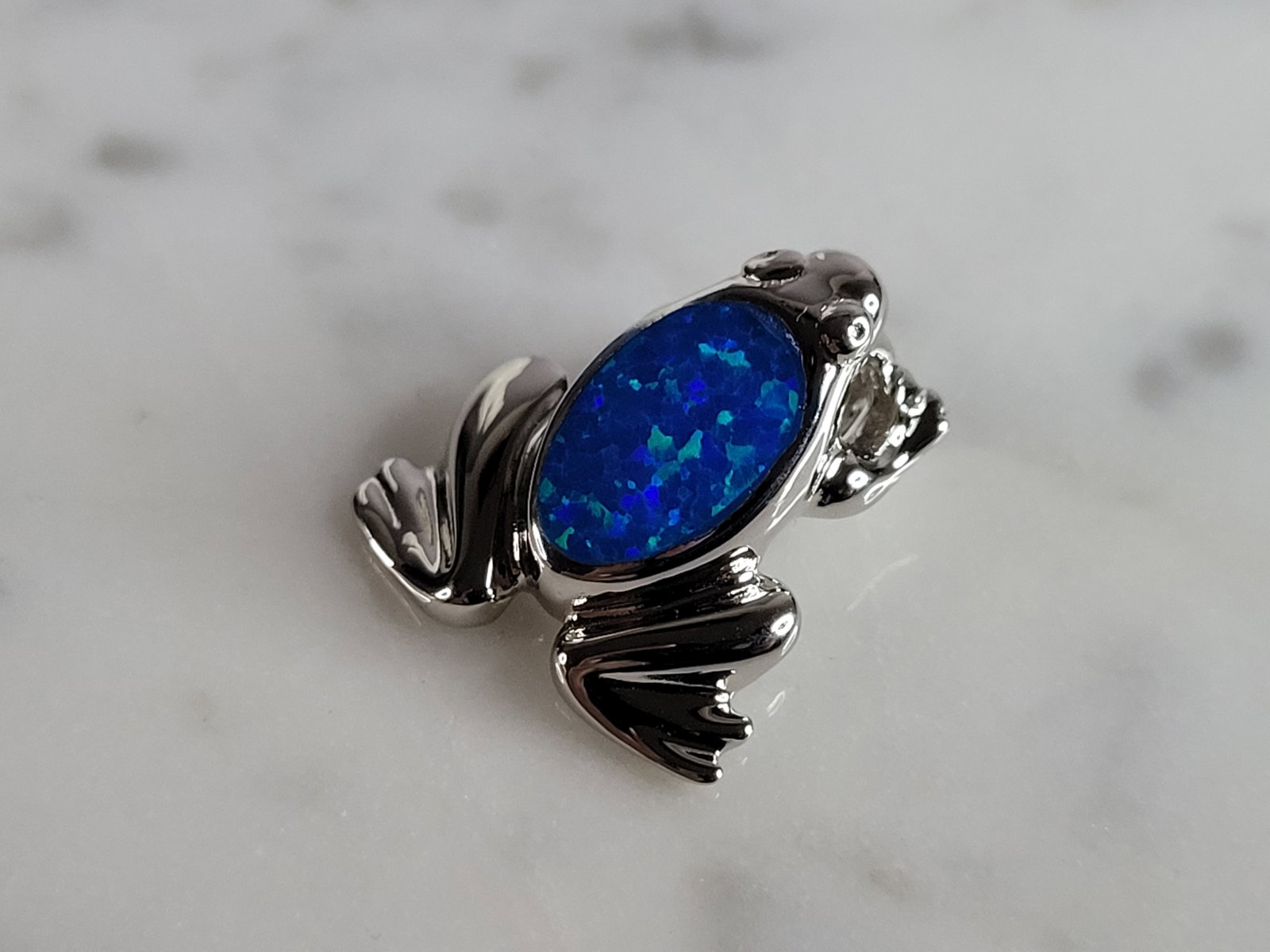 Womens Sterling Silver Blue Opal Frog Pendant: A WOMENS STERLING SILVER BLUE OPAL FROG PENDANT. NOT SURE IF STONES ARE REAL OR MAN MADE. THE PENDANT WEIGHS 3.0g AND MEASURES 5/8" LONG BY 5/8" WIDE. MAKES A GREAT GIFT FOR THAT SOMEONE SPECIAL. ANY 