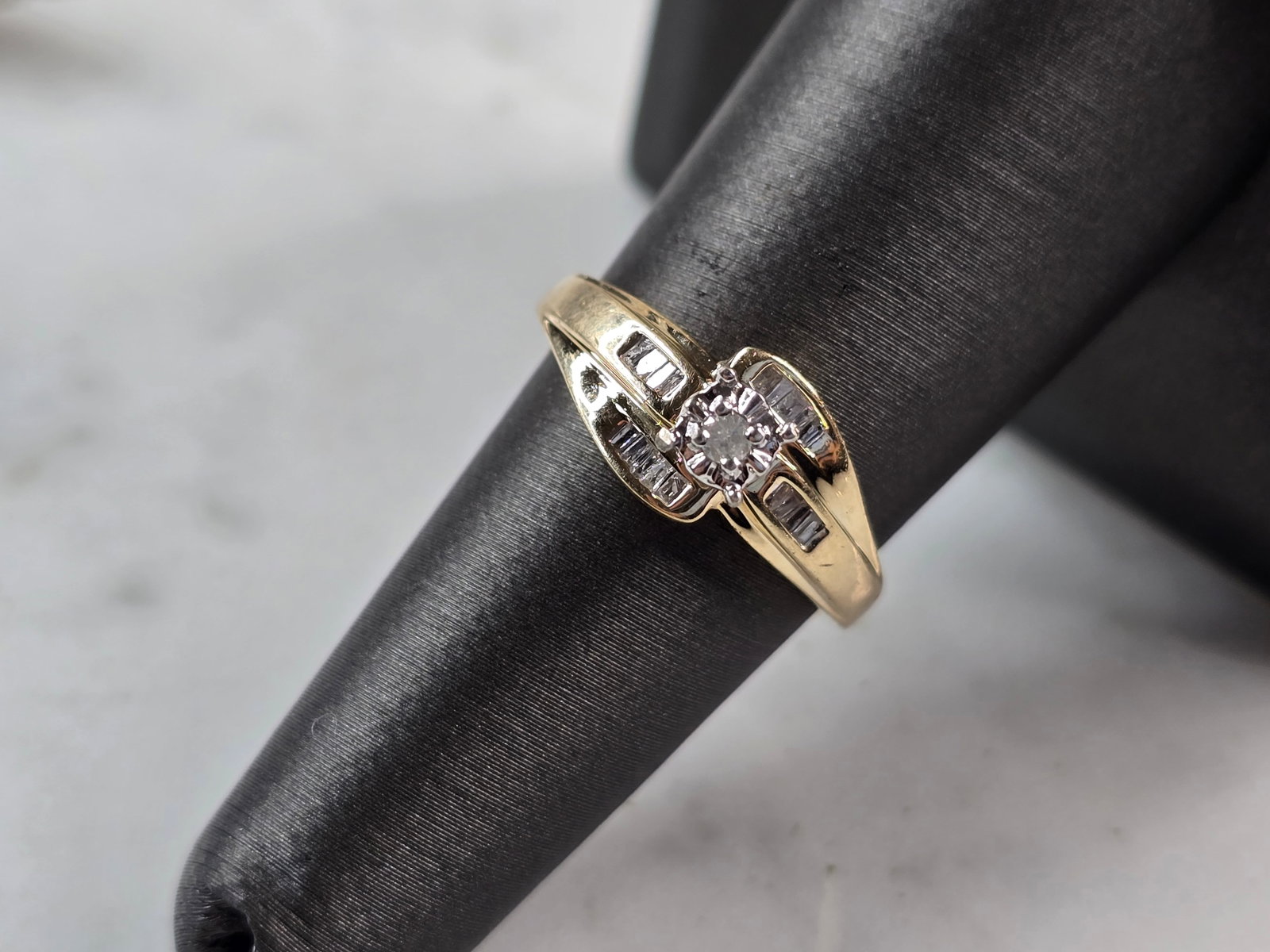 Womens Vintage Estate 10K Yellow Gold Ring Diamond Ring: A WOMEN'S VINTAGE ESTATE 10K YELLOW GOLD DIAMOND RING. THE RING IS A SIZE 7.0, AND WEIGHS 3.0g. THE WIDTH OF THE RING IS 3/8". THE CENTER DIAMOND IS ABOUT .03cts SURROUNDED BY 18 BAGUETTES. THIS IS A 