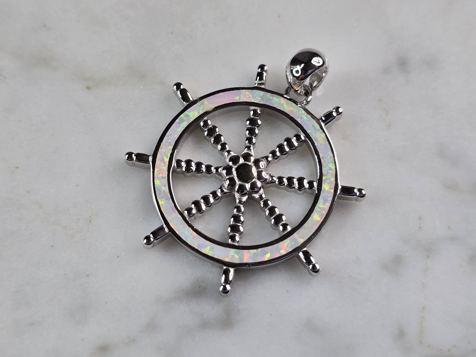 Womens Sterling Silver Opal Maritime Ship Wheel Pendant: A WOMENS STERLING SILVER OPAL MARITIME SHIPS WHEEL PENDANT. THE PENDANT WEIGHS 4.5g AND MEASURES 1 1/4" LONG BY 1 1/8" WIDE. NOT SURE IF STONES ARE NATURAL OR MAN MADE. MAKES A GREAT GIFT FOR THAT SOM