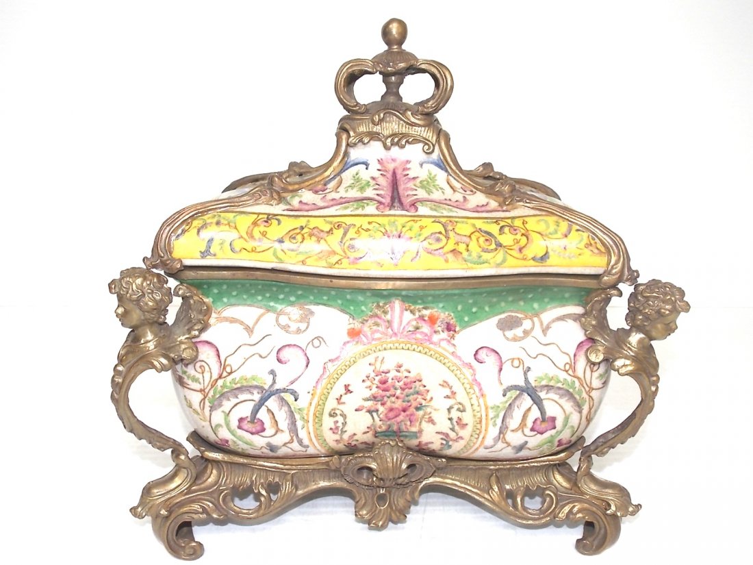 VICTORIAN STYLE FLORAL PORCELAIN FOOTED CASKET URN: A Victorian art nouveau style porcelain footed bowl with lid and what I believe to be brass or bronze cherubs, and accents decorating the piece. The piece measures about 15 1/2" tall, by 14 1/2" long 