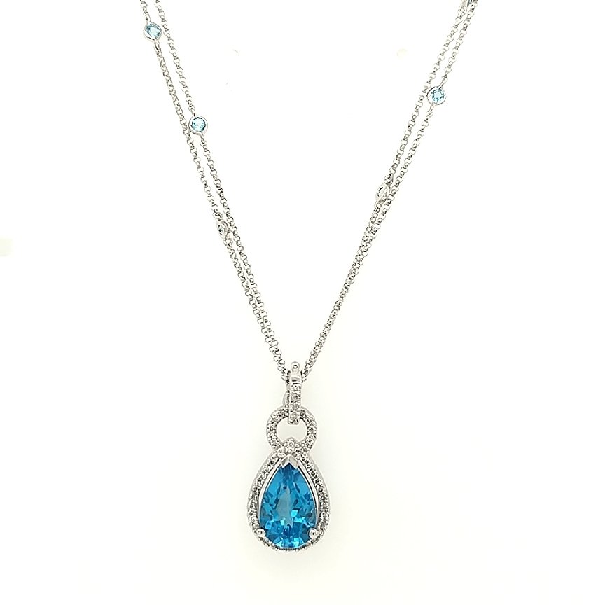 A Blue Topaz & Diamond Pendant: Crafted in 14k white gold featuring (1) pear shaped blue topaz weighing approximately 3.50ct and (5) round diamonds weighing .22cttw. The pendant is 1" in length. The chain is a double strand with (8)
