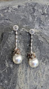 South Sea Pearl and Diamond Earrings: Crafted in 18k white gold featuring (2) round pearls measuring 13mm. The drop contains a mixture of white and champagne colored diamonds with a mixture of shapes including marquis, rose cut and briole