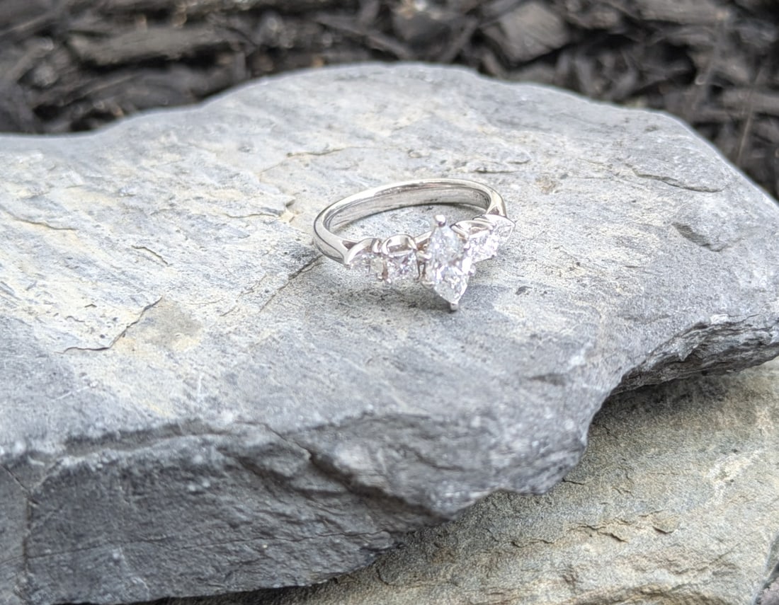 Marquise Diamond Engagement Ring: Crafted in 14k white gold featuring (1) marquise diamond weighing approximately .71ct with color of I/J and a clarity of SI. There are also (2) princess cut diamonds weighing approximately .23cttw wit