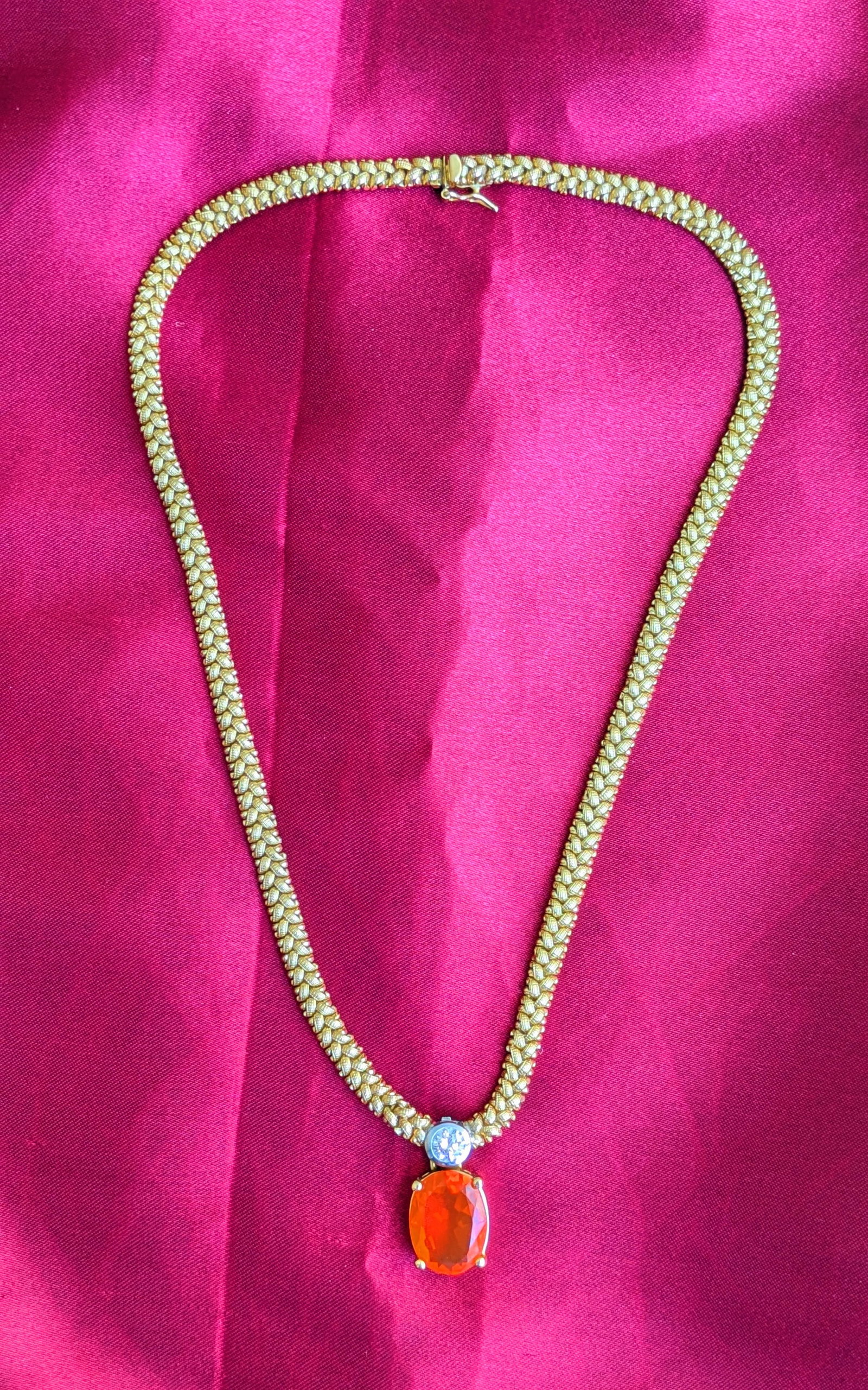 Fire Opal and Diamond Necklace: Crafted in 14k yellow gold featuring (1) fire oval opal measuring 17.2mm x 12.9mm x 7.4mm and weighing approximately 6.50ct. The diamond is bezel set and weighs approximately .75ct with a G/H color an