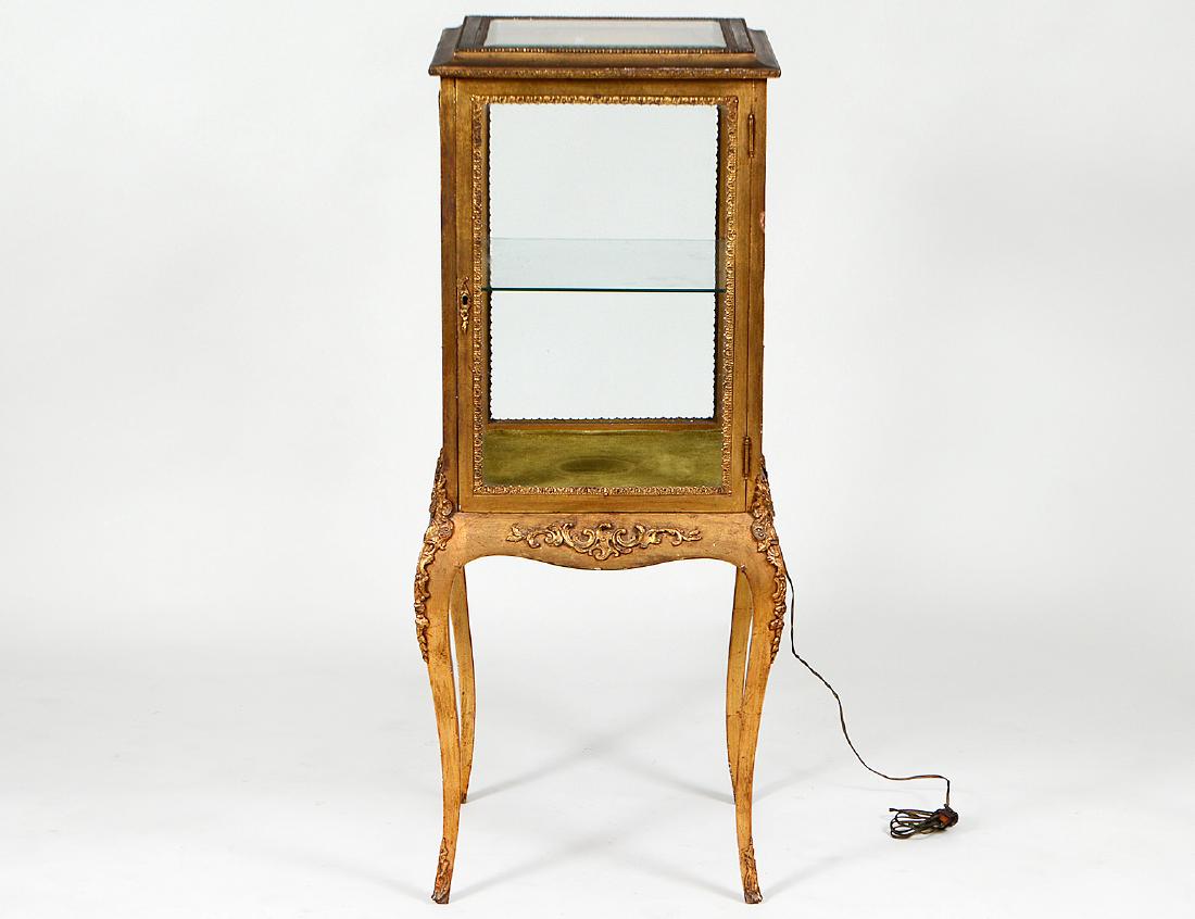 ROCOCO STYLE GILT WOOD CENTER VITRINE: Early 20th Century. With a glazed top and all around glazed panels, within borders of gilt metal, one with a hinged door, the shaped skirt on cabriole legs, with one glass shelf, electrified. Height 4