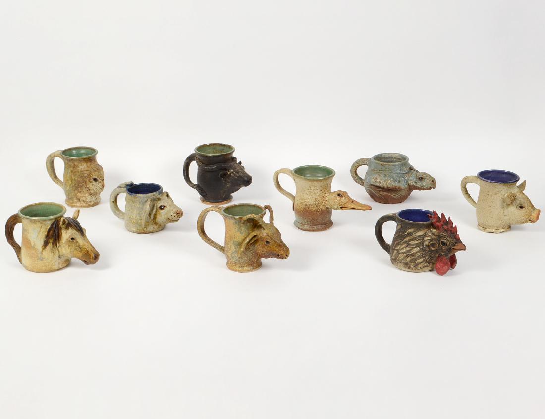 TWELVE WHIMISCAL ANIMAL HEAD EARTHENWARE MUGS: Modern. Unsigned. Each with a different animal's head applied to the body, some with glass inset eyes, each with a loop handle. Heights 3 ½” to 5 ¼”. (Cond: good) (250/350)