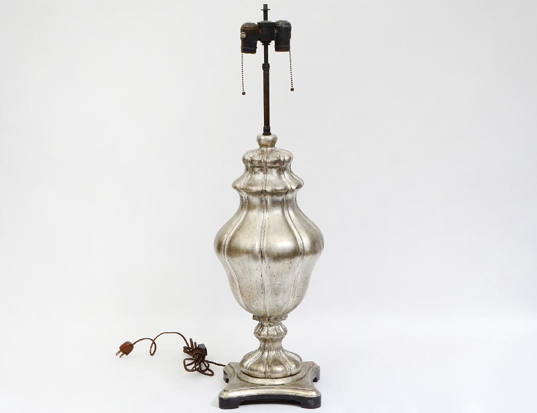 ROCOCO STYLE SILVERED WOOD URN-FORM LAMP: Modern. Of baluster shape, on a shaped square base, electrified. Height 22 ½”, overall 33”. (Cond: good) (200/300)