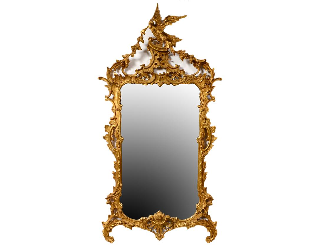 GEORGE III STYLE GILTWOOD MIRROR: Modern. In the manner of Thomas Chippendale. The rectangular mirror plate within a surround carved with leaves, scrolls and a pair of Ho-Ho birds. Height 5’. Width 32”. (Cond: good) (500/700)