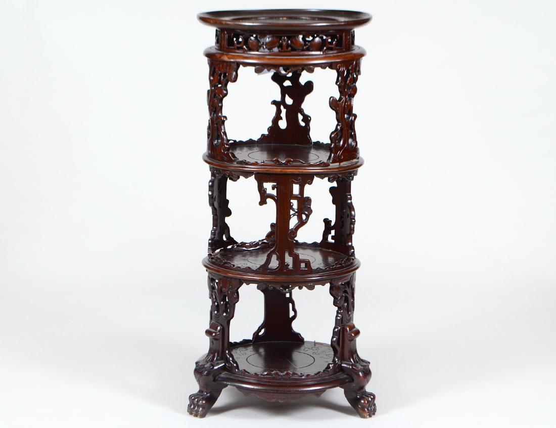 UNUSUAL CARVED WALNUT FOUR-TIER CIRCULAR ETAGERE: Possibly Japanese. Early 20th Century. Each circular tier above a pierced prize or raised on pierced supports, on foliate carved paw feet. Height 38”. Diameter of upper tier 16 ½”. (Cond: some ol