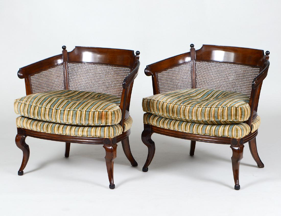 PAIR OF CONTINENTAL CANED MAHOGANY TUB CHAIRS: Modern. Each curved crest rail continuing to form the arms, above a tripart caned back, with upholstered seat and loose cushion, on scroll-curved legs. (Cond: good, surface stained) (300/500)