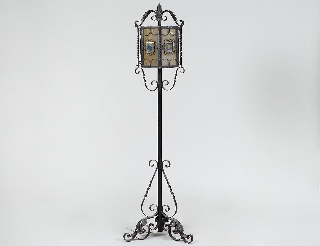SPANISH BAROQUE STYLE WROUGHT IRON FLOOR LAMP: Circa 1900. The hexagonal shaped upper part fitted with glass plates, on a standard with three scrolled supports. Height 5’ 6”. Width 15 ½”. (Cond: glass plates loosely affixed, probably later)