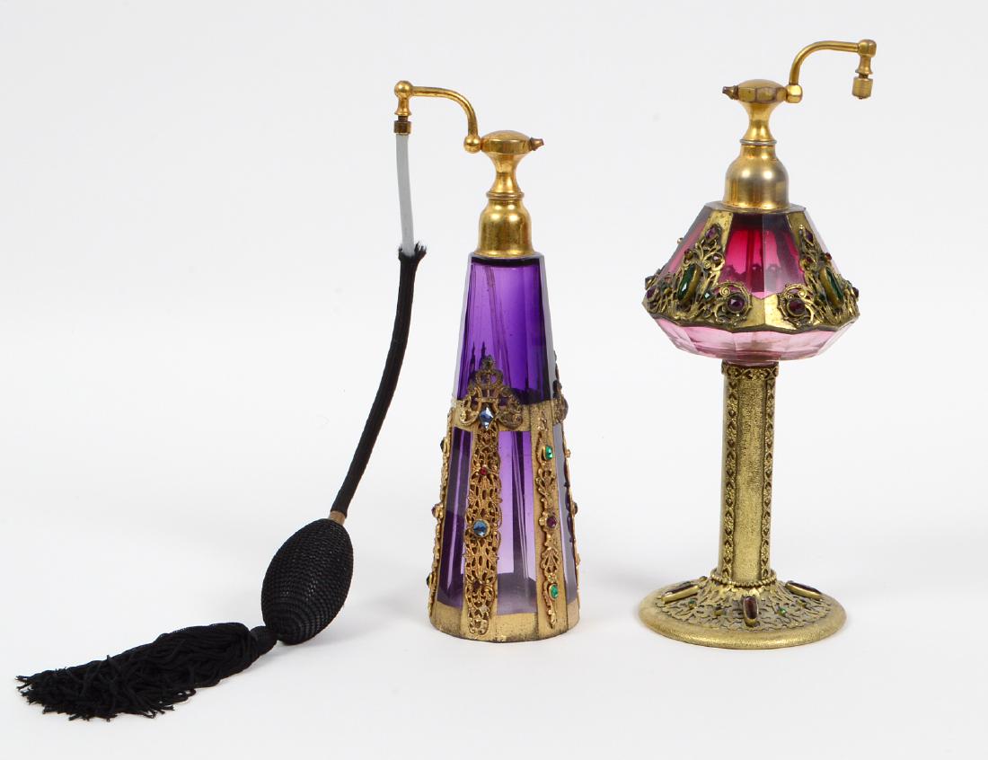 TWO CZECH GILT & JEWEL MOUNTED AMYTHEST GLASS PERFUMES: Early 20th Century. One with markings. Each with atomizers, gilt metal mounts and colored stones. Heights 9 ¾”, 8 ¼”. (Cond: good) (200/300)