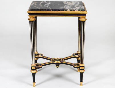 LOUIS XVI STYLE MARBLE INSET GILT & EBONIZED TABLE: In the manner of Adam Weisweiler. The white veined black marble with gilt wood and ebonized border, raised on circular tapering fluted legs joined by a cross stretcher, on toupee feet. Height 30 ½”