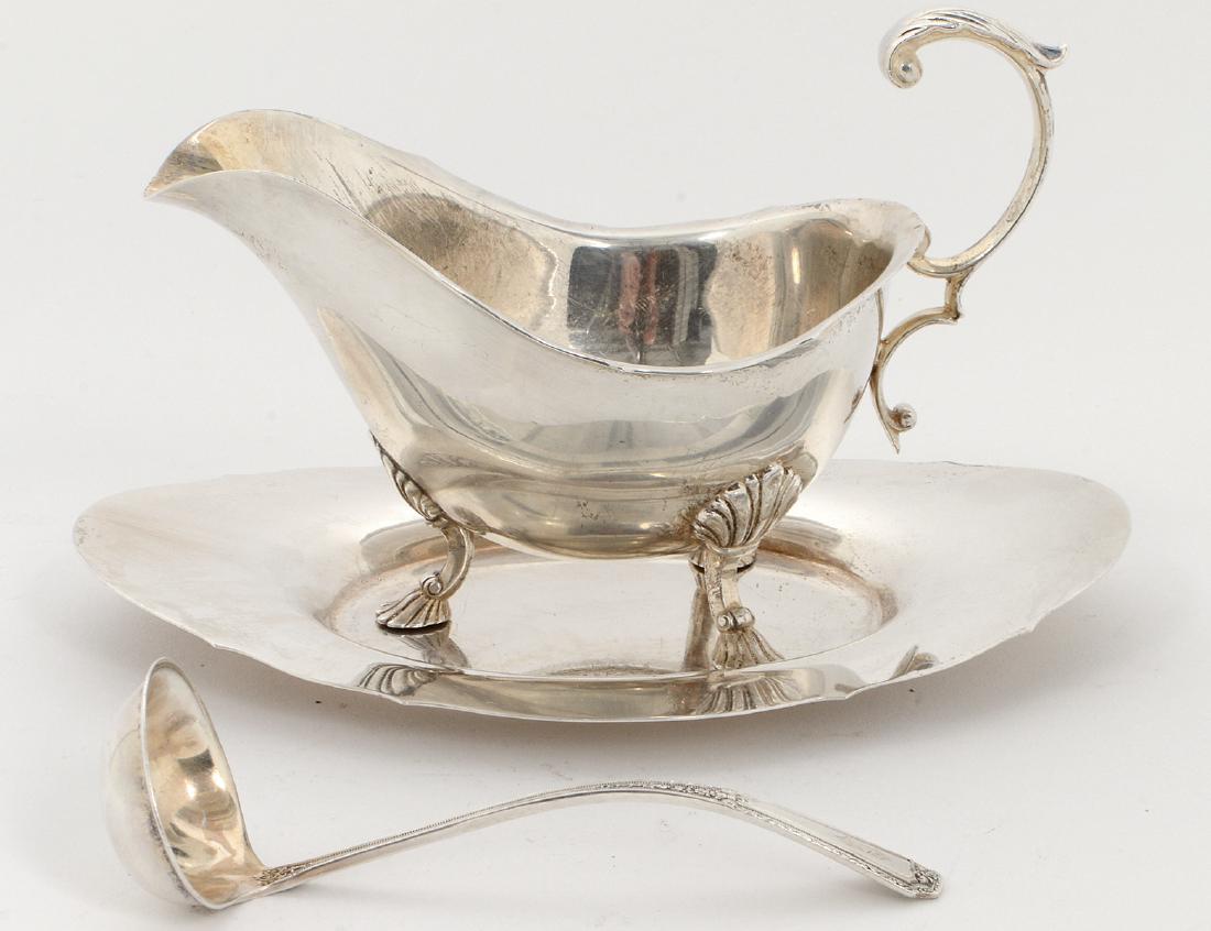 STERLING SILVER SAUCE BOAT, UNDER PLATE & LADLE: 20th Century. Marked Sterling, Poole with an etched rampant lion. The boat of typical form, with a scrolled handle, and tripod shell and hoofed feet. Length of plate 8 ¼”. (Cond: good) (300/500)