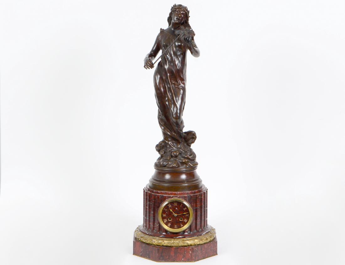NAPOLEAN III BRONZE AND RED MARBLE FIGURAL CLOCK: French. Circa 1880. Signed J. Garnier. The classically dressed female musician playing the violin, atop a fluted red marble base, set with a clock face, atop an octagonal plinth, with gilt bronze coll