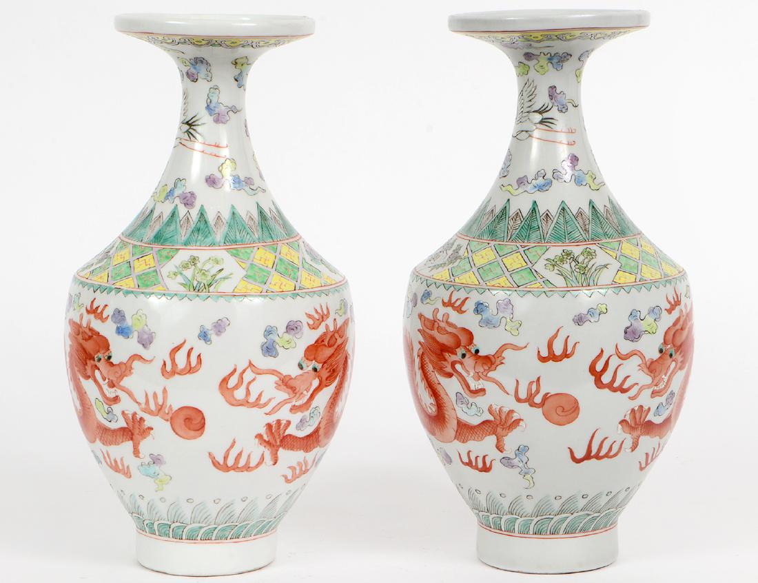 PAIR OF CHINESE ENAMEL DECORATED PORCELAIN VASES: Each with a four-character chop mark in iron red. The tapered vessels, with a flared neck and disc-form rim, with feathered, foliate and wave borders, centering dragons in iron red. Height 12". Diamet