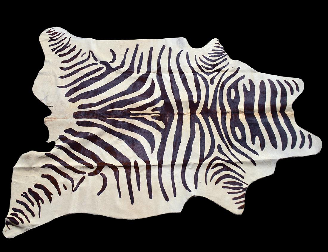 ZEBRA SKIN RUG: Length 7’2". Width 5’ 10". (Cond: minor areas of wear to center & sides, small tear to one side, otherwise good)