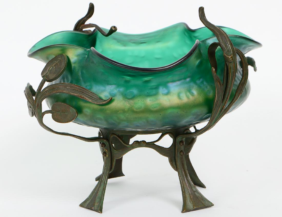 ART NOUVEAU LOETZ STYLE GLASS BOWL ON STAND: Circa 1900. Unsigned. The undulating iridescent green glass bowl on a patinated metal stand. Height overall 7 3/4". Diameter 9". (Cond: good)