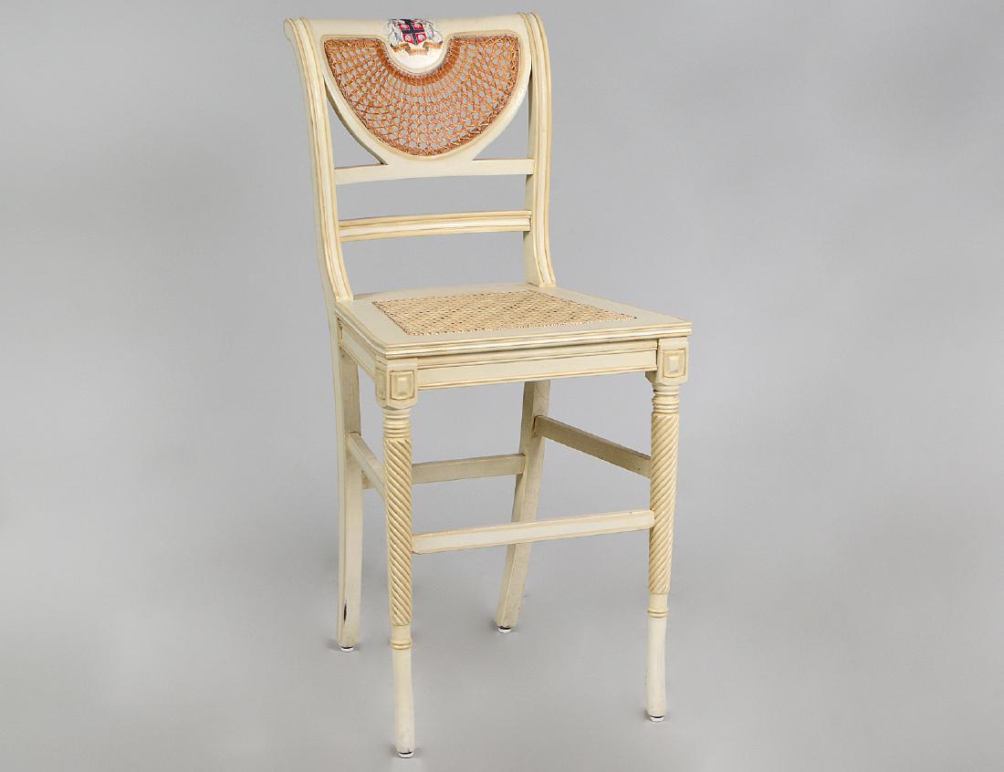 REGENCY STYLE PAINTED AND CANED BAR STOOL: Modern. Clive Christian. The shaped back with a caned panel, the crest with a painted armorial. The caned seats on long spiral carved circular flared legs. Height back to floor 41", seat to floor 26".