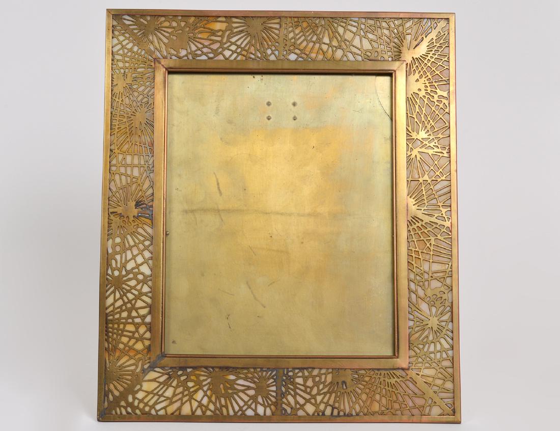 LARGE TIFFANY STUDIOS SLAG GLASS & BRASS FRAME: Circa 1910. The reverse impressed Tiffany Studios New York, numbered 916. Pierced, in the "Spider Web" pattern, with caramel glass.Measuring 14 inches high, 12 inches wide. (Cond: good). PROVENANCE: F