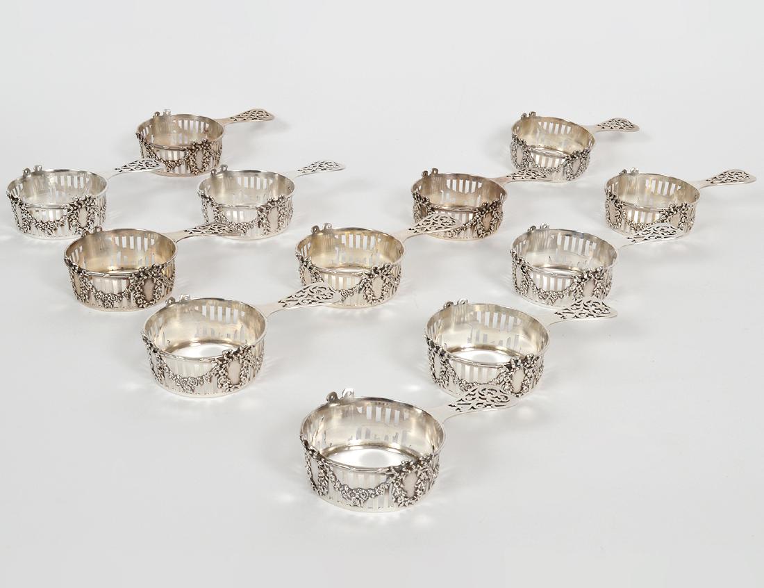 TWELVE AMERICAN STERLING SILVER RAMEKIN HOLDERS: 20th Century. Marked Sterling, Spaulding & Co., numbered 2314. In a neo-classical style, each vertically pierced and chased with bow-tied garlands, the handle with open work scrolls. Troy oz. 23.5. Le