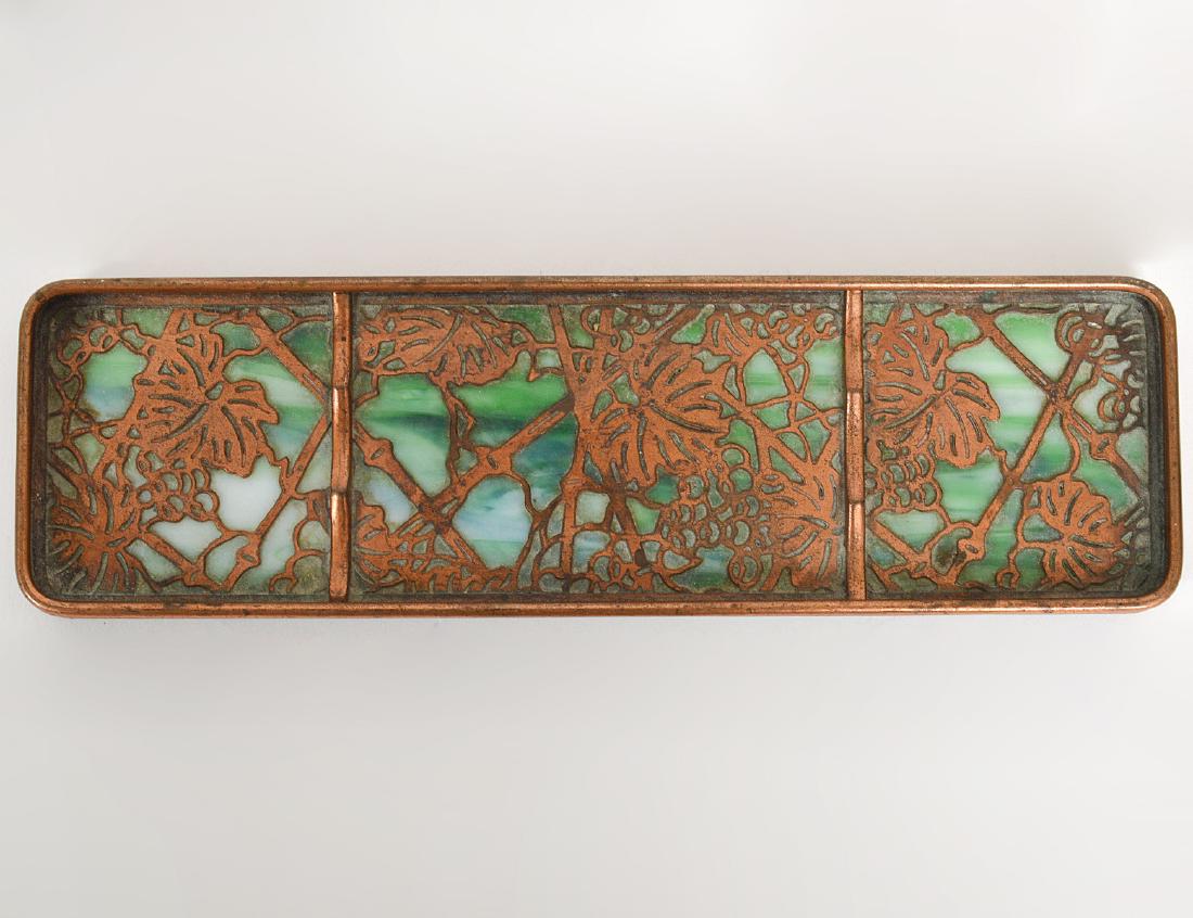 TIFFANY STUDIOS COPPER & GREEN GLASS PEN TRAY: Circa 1900. Signed Tiffany Studios, New York. Numbered 1004. In the "Grape Vine" pattern. Length 9 1/2". (Cond: good)