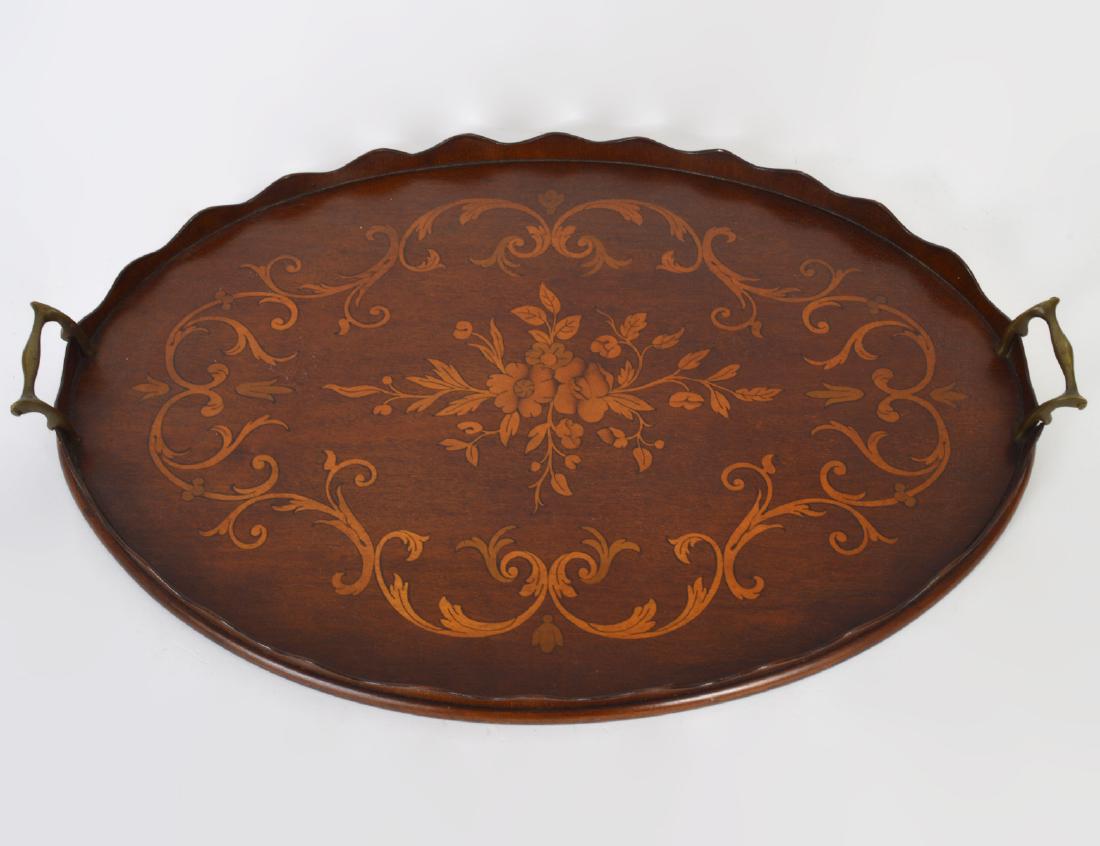 EDWARDIAN FRUITWOOD MARQUETRY MAHOGANY TRAY: Circa 1900. Oval with a scalloped wood gallery and brass bail handles, inlaid with a center floral spray within all around scrolls. Length 24”. (Cond: good)